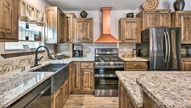 Una cocina con armarios de madera, un refrigerador de acero inoxidable, una estufa a gas y un horno empotrado.