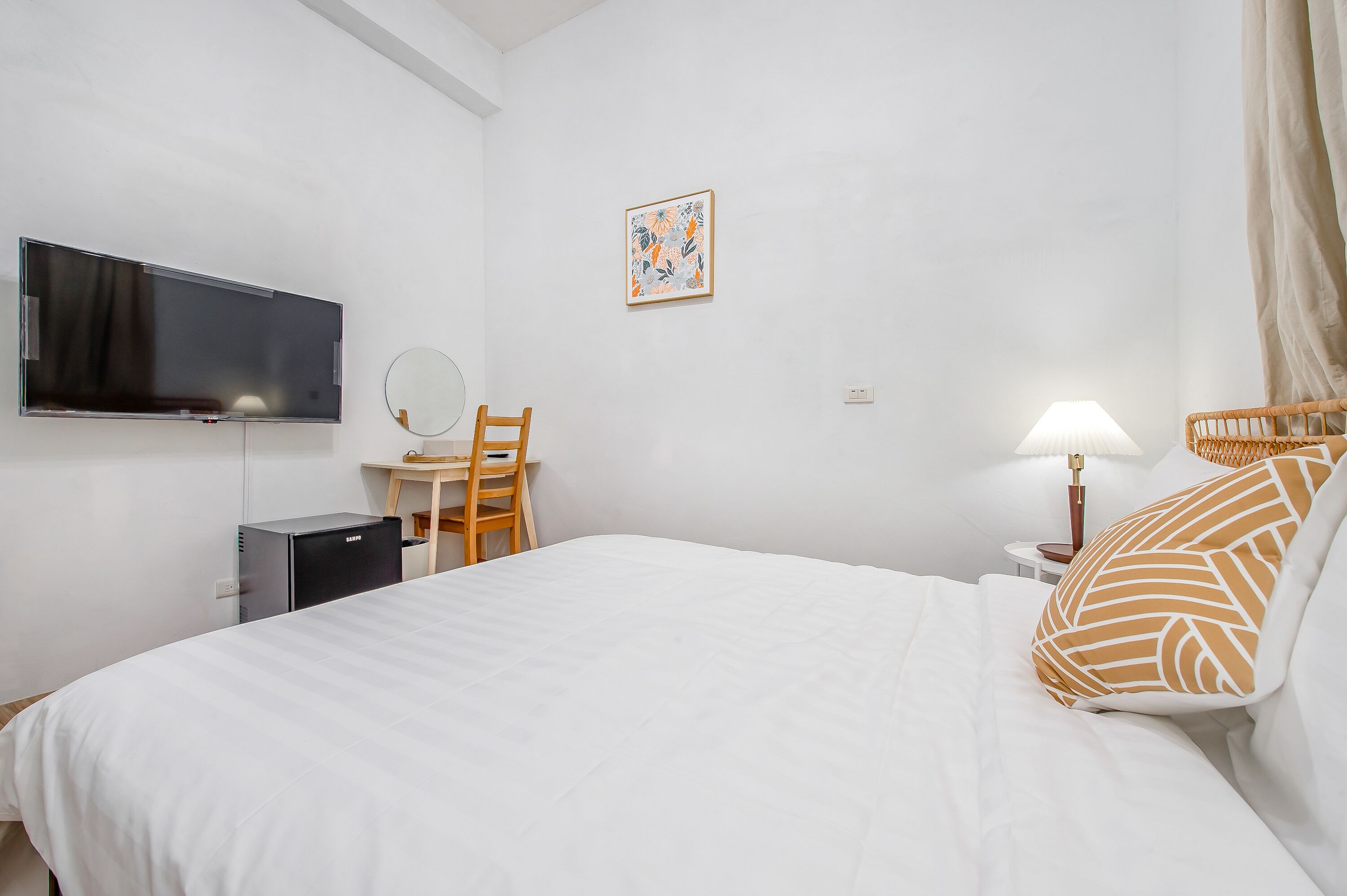 Ett hotellrum med en säng, ett skrivbord med en stol, en tv, en lampa och ett litet bord.