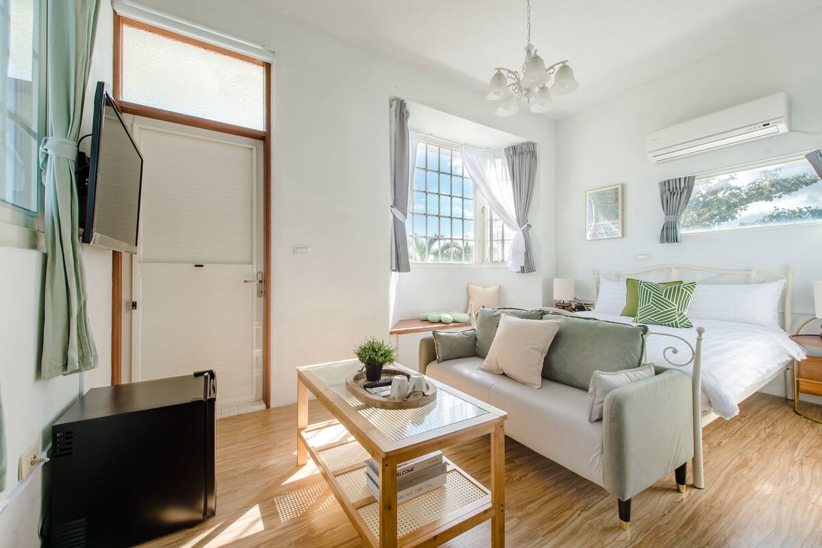 Une chambre à coucher moderne avec un lit, une table de chevet et une fenêtre avec des rideaux.