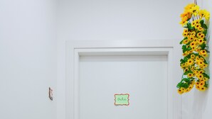 Une porte blanche avec une enseigne portant l’inscription « Orchid » au-dessus, une petite plante d’orchidée rose sur la gauche et une composition florale jaune sur la droite.