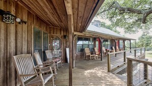 Una terraza de madera con mecedoras y una zona cubierta con mesas y sillas.