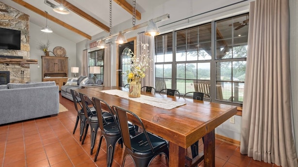 Un comedor amplio con una larga mesa de madera, sillas negras y vistas al exterior a través de grandes ventanas.