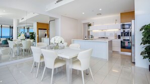 Een moderne keuken met witte kastjes, een centraal eiland en inbouwapparatuur.
