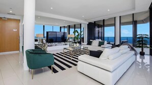 Een moderne woonkamer met een witte bank, een gestreept vloerkleed en een televisie.