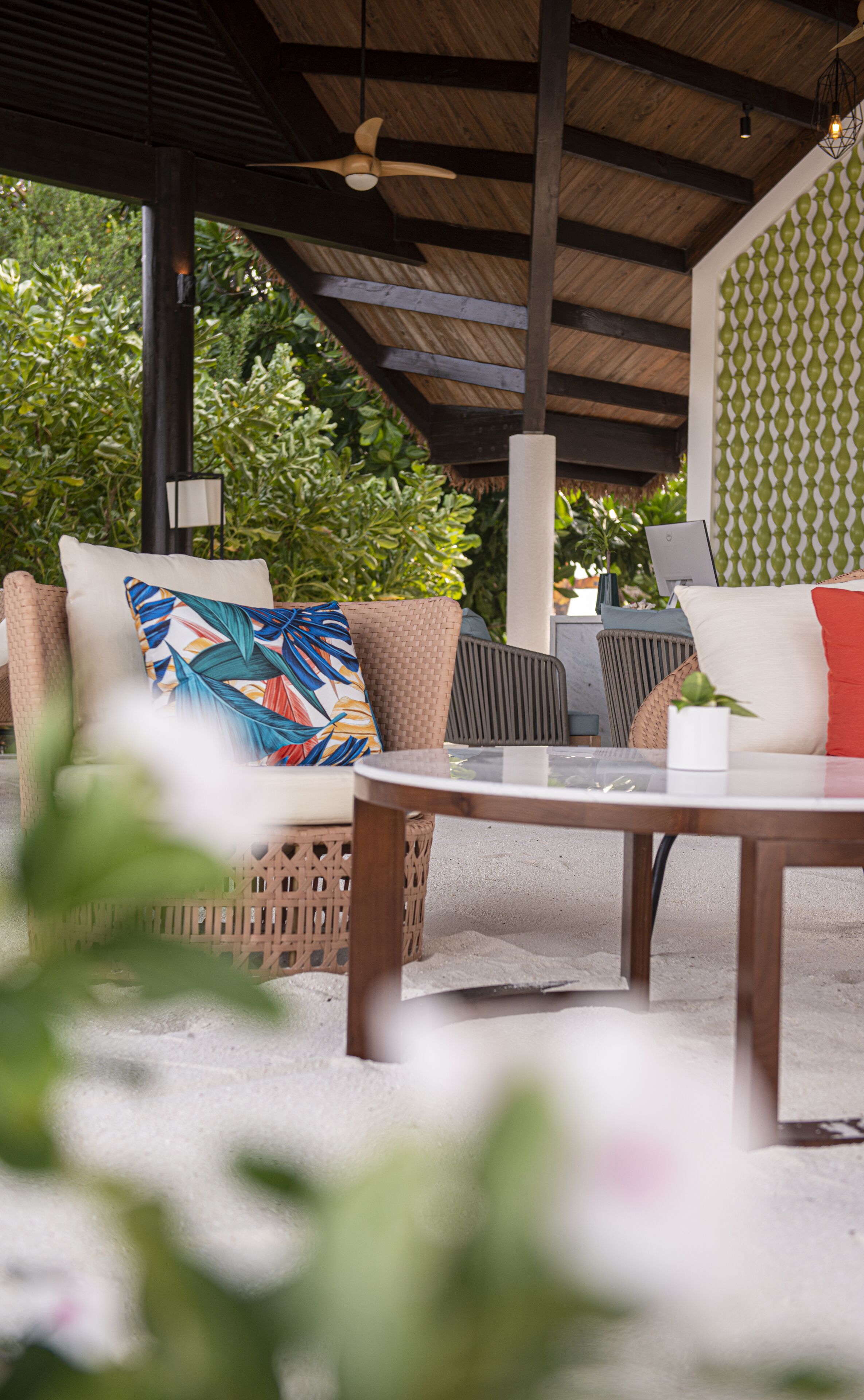 An outdoor seating area with wicker furniture, a round table, and a ceiling fan.