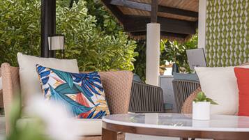 An outdoor seating area with wicker furniture, a round table, and a ceiling fan.