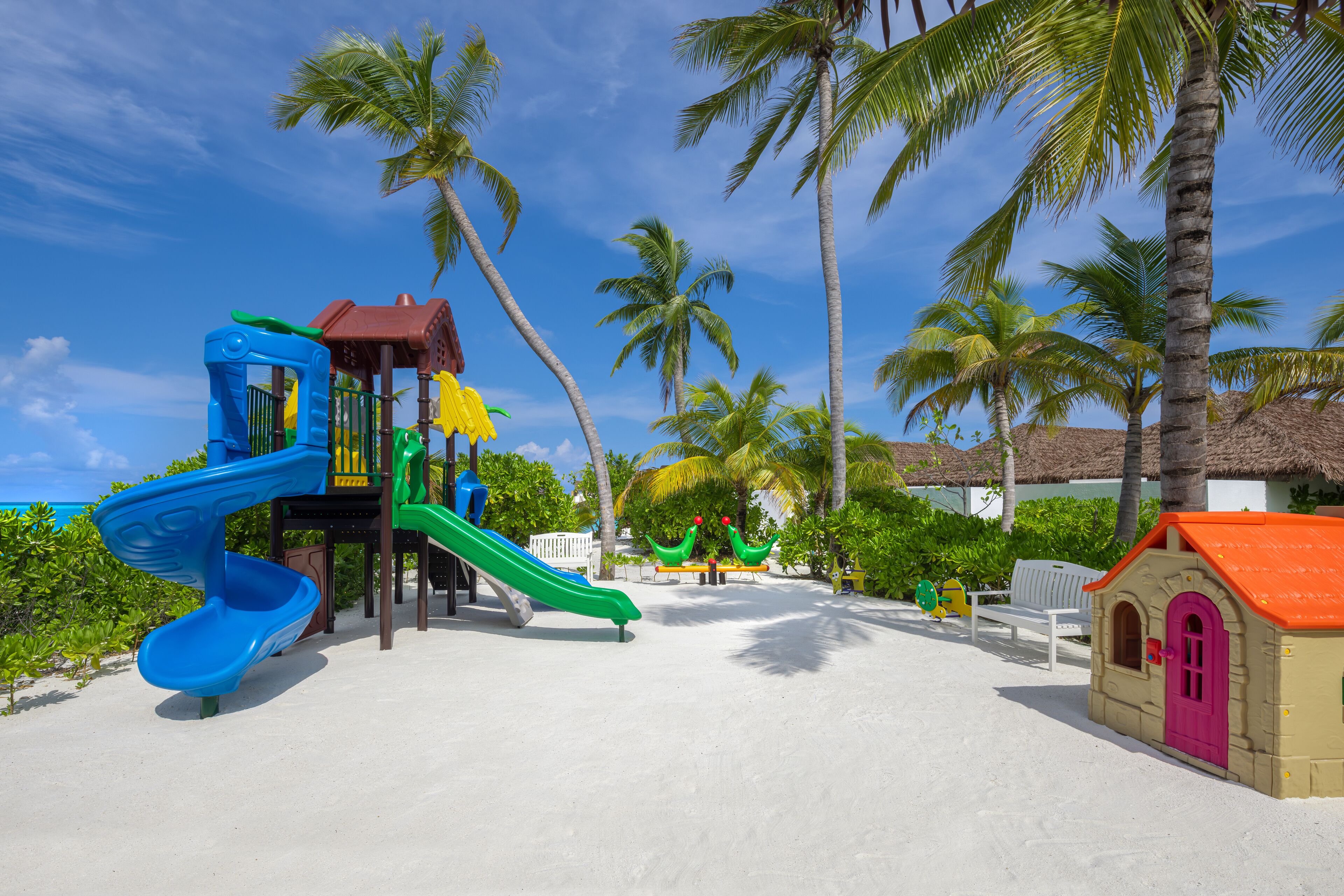 A beach playground with slides and a small building.