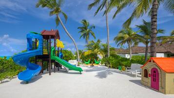 A beach playground with slides and a small building.