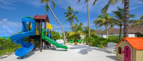 Une aire de jeux de plage avec des toboggans et un petit bâtiment.