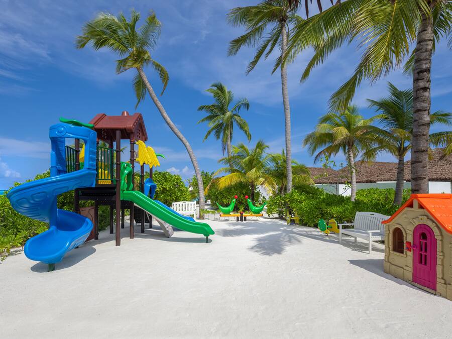 A beach playground with slides and a small building.