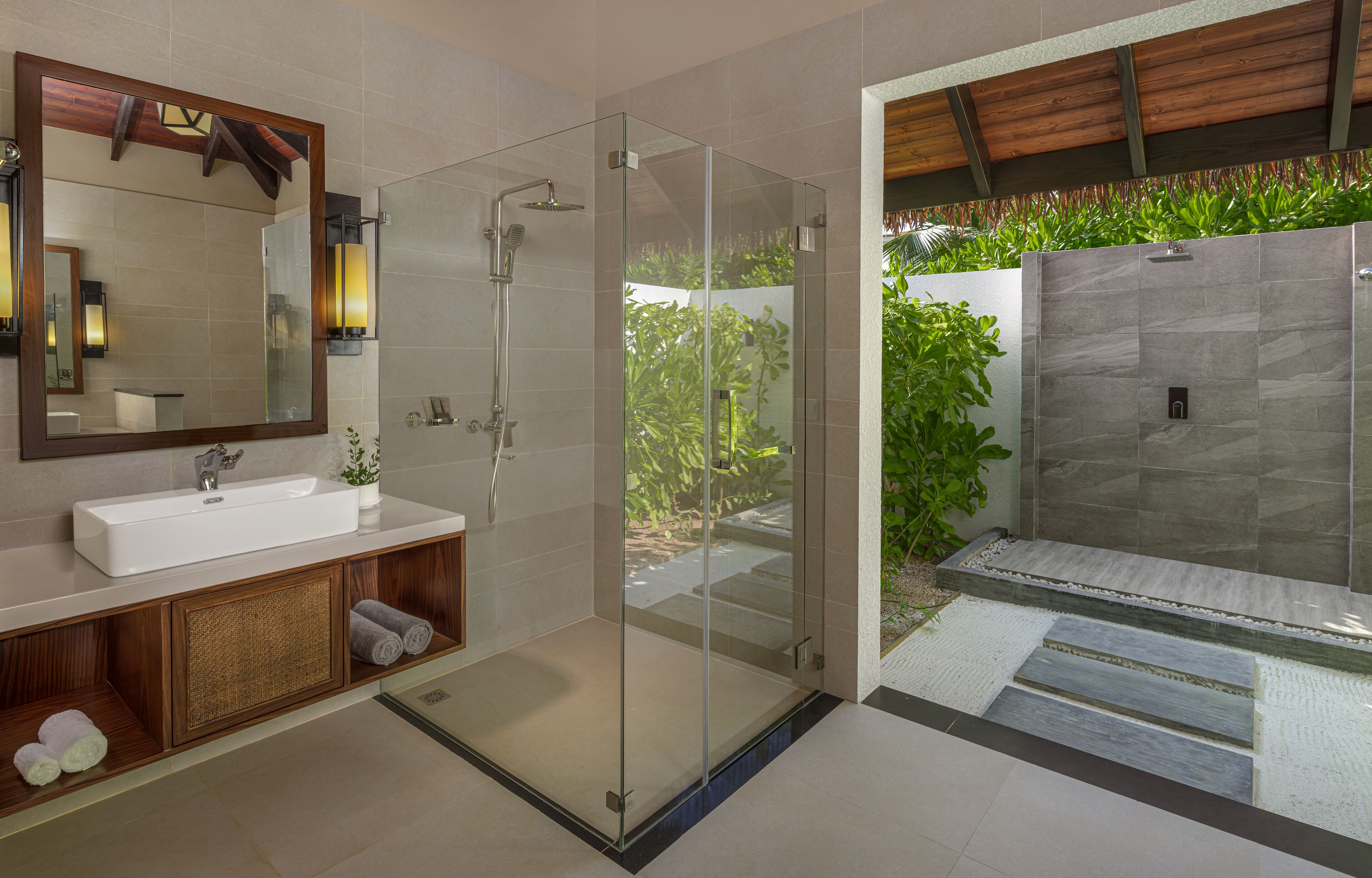A modern bathroom with a glass-enclosed shower, a large mirror, and a sink with a wooden vanity.