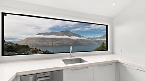 A kitchen with a large window overlooking a mountainous landscape and a lake. - Large Pure Alpine Privacy and Recently Renovated (Queenstown)