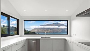 A modern kitchen with a large window offering a view of mountains and a lake. - Large Pure Alpine Privacy and Recently Renovated (Queenstown)