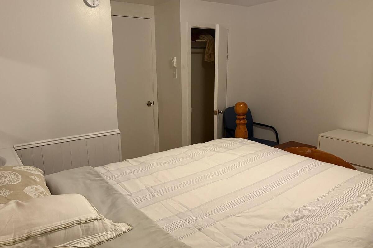 Une chambre à coucher comprenant un lit, une chaise, une armoire et une table de chevet.