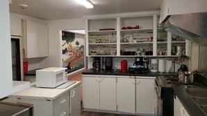 Een keuken met witte kastjes, een magnetron, een koffiezetapparaat en een schilderij aan de muur.