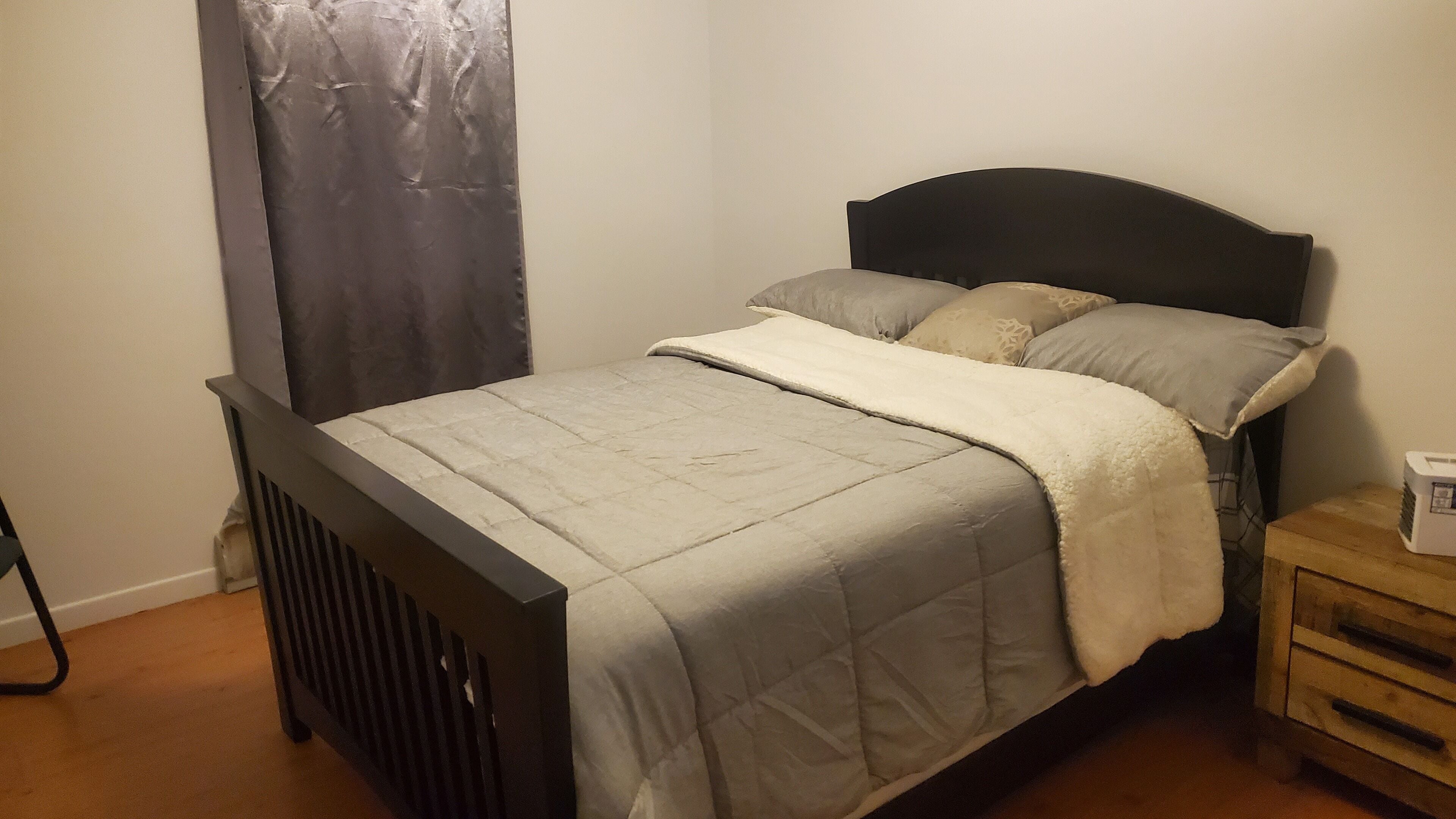 A bedroom with a bed, a nightstand, and a radiator.