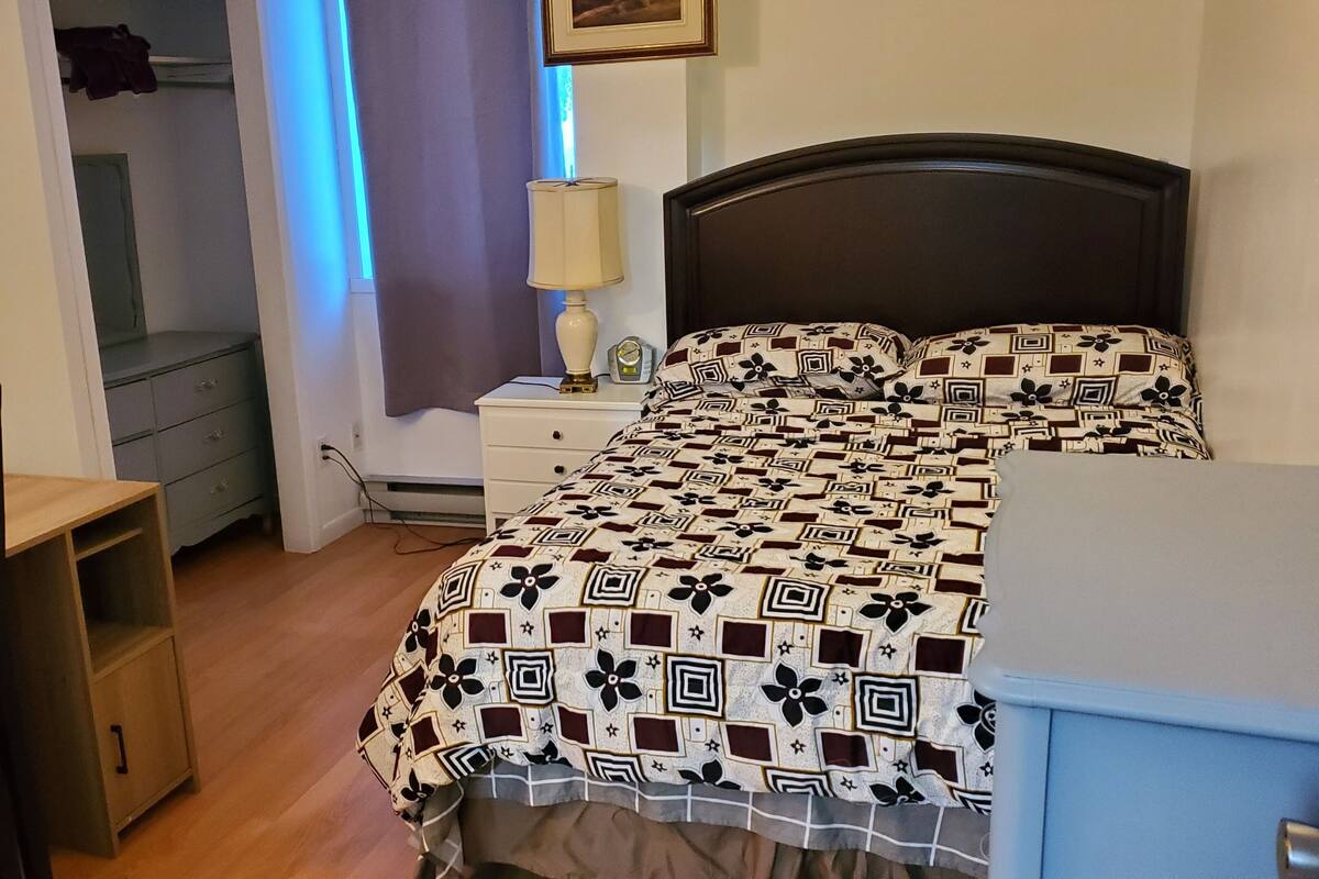 Une chambre à coucher comprenant un lit, un bureau, une chaise, une table de chevet et une lampe.