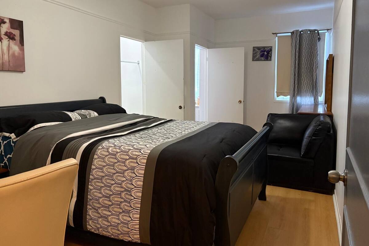 Une chambre à coucher avec un lit, une chaise, une porte et une fenêtre avec des rideaux.