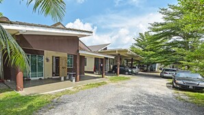 A building with a covered outdoor area, a gravel driveway, and parked cars. - OYO HOME 90646 Casaria Paka Homestay (Dungun)
