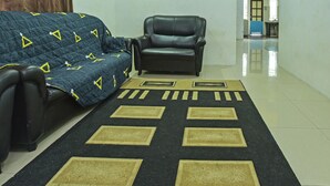 A living room with a sofa, a chair, and a patterned rug. - OYO HOME 90646 Casaria Paka Homestay (Dungun)