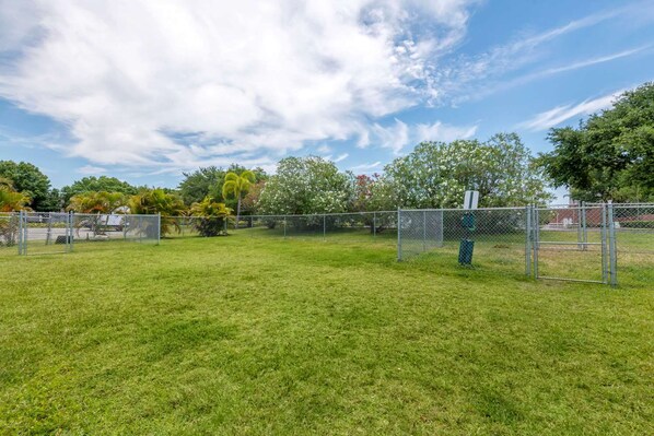 A fenced outdoor area with grass, trees, and a clear sky. - Comfort Inn & Suites Melbourne Viera (Melbourne)
