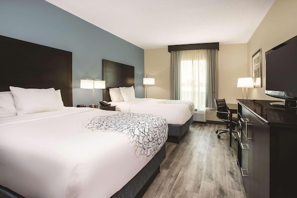 A hotel room with two beds, a desk, a chair, a TV, and a large window with curtains. - Comfort Inn & Suites Melbourne Viera (Melbourne)