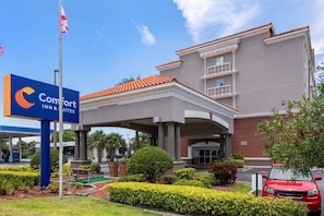 A Comfort Inn & Suites hotel with a covered entrance, palm trees, and a red car parked in front. - Comfort Inn & Suites Melbourne Viera (Melbourne)