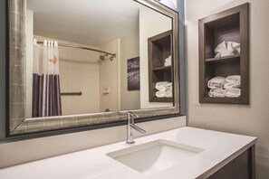 A bathroom with a large mirror, a white sink, and a towel rack with folded towels. - Comfort Inn & Suites Melbourne Viera (Melbourne)