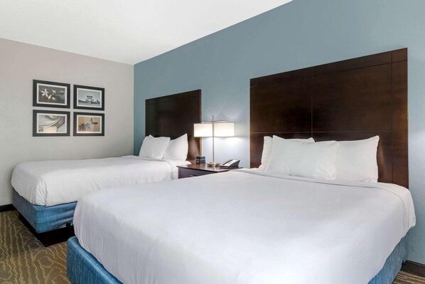 A hotel room with two beds, a nightstand with a lamp, and four framed pictures on the wall. - Comfort Inn & Suites Melbourne Viera (Melbourne)