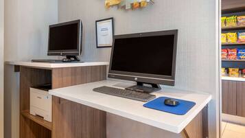 A clean, modern workspace with two desktop computers, a keyboard, and a mouse on a white desk.