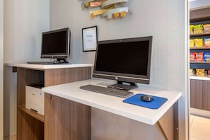 Ein aufgeräumter, moderner Arbeitsplatz mit zwei Computern, einer Tastatur und einer Maus auf einem weißen Schreibtisch.