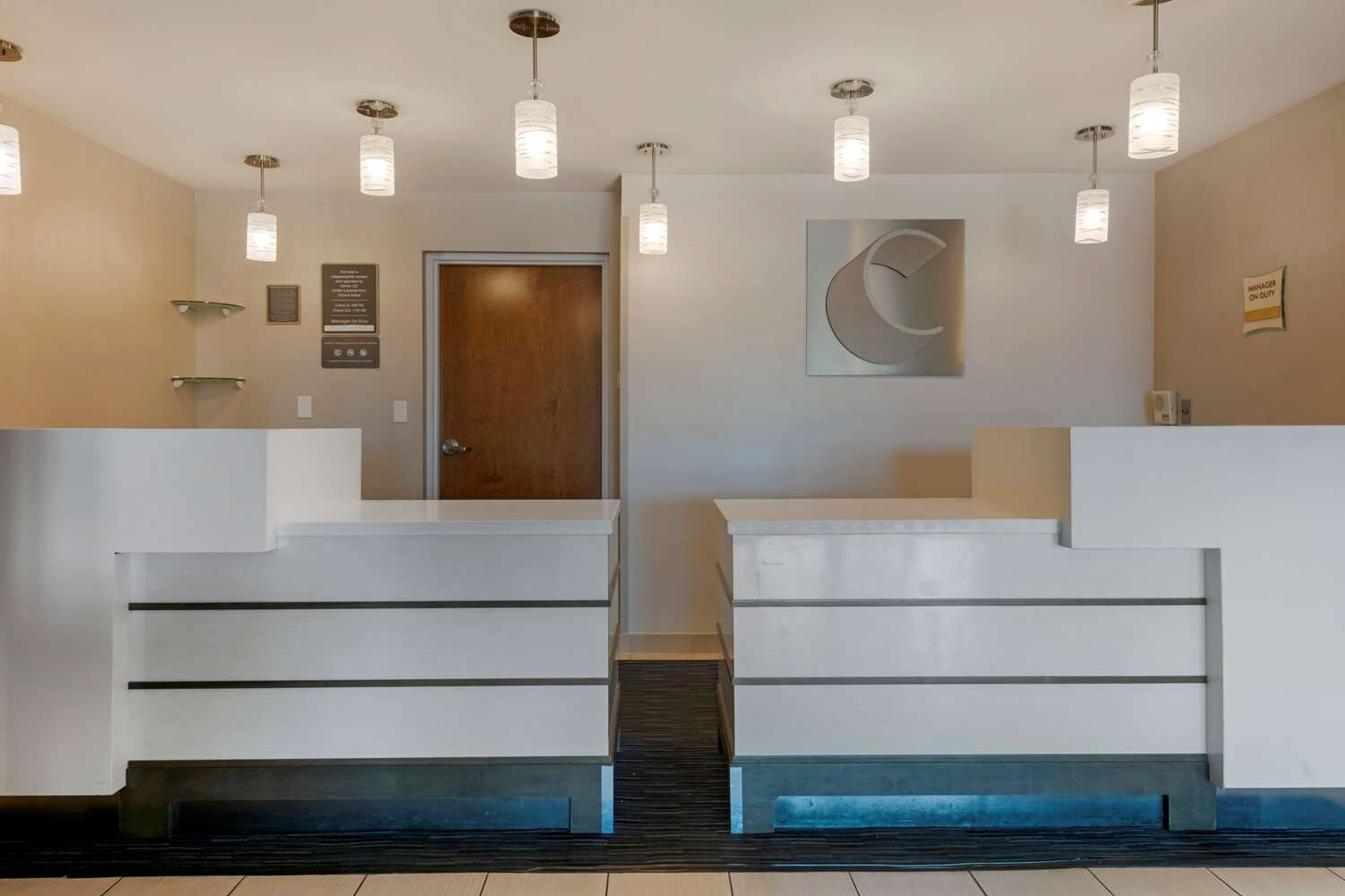 A reception area with a modern staircase, a wooden door, and a wall-mounted sign.