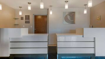 A reception area with a modern staircase, a wooden door, and a wall-mounted sign.