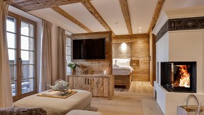 Ein gemütliches Zimmer mit Kamin, Bett, Fernseher und Holzschrank.