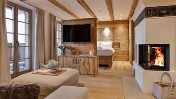 Ein gemütliches Zimmer mit Kamin, Bett, Fernseher und Holzschrank.