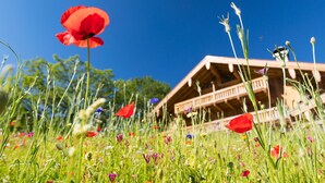 Eine Holzhütte mit einem Balkon, umgeben von einem Feld mit Wildblumen.