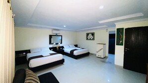 A hotel room with two beds, a sofa, a small table, a mirror, and a door. - Dedy Beach Inn (Kuta)