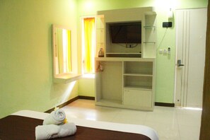 A hotel room with a bed, a television, a wardrobe, and a window with curtains. - Dedy Beach Inn (Kuta)