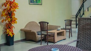 A room with wicker furniture, a potted plant, and a staircase. - Dedy Beach Inn (Kuta)