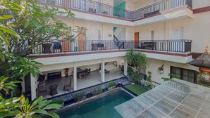 A multi-level hotel with balconies, a swimming pool, and indoor plants. - Dedy Beach Inn (Kuta)