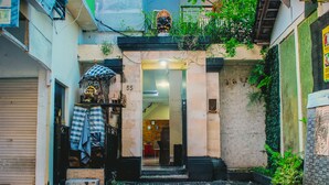 A narrow alley with a cobblestone path, a number '55' sign, and a small shop with a checkered umbrella. - Dedy Beach Inn (Kuta)