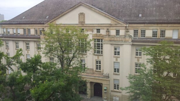 Un edificio grande e histórico con fachada simétrica, numerosas ventanas y una entrada central.