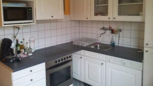 Una cocina con armarios blancos, un microondas, una estufa y un lavabo.