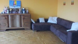 Una sala de estar con un mueble de madera, un sofá oscuro y un cuadro en la pared.