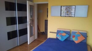 Un dormitorio con cama, armario y puerta que da a otra habitación.