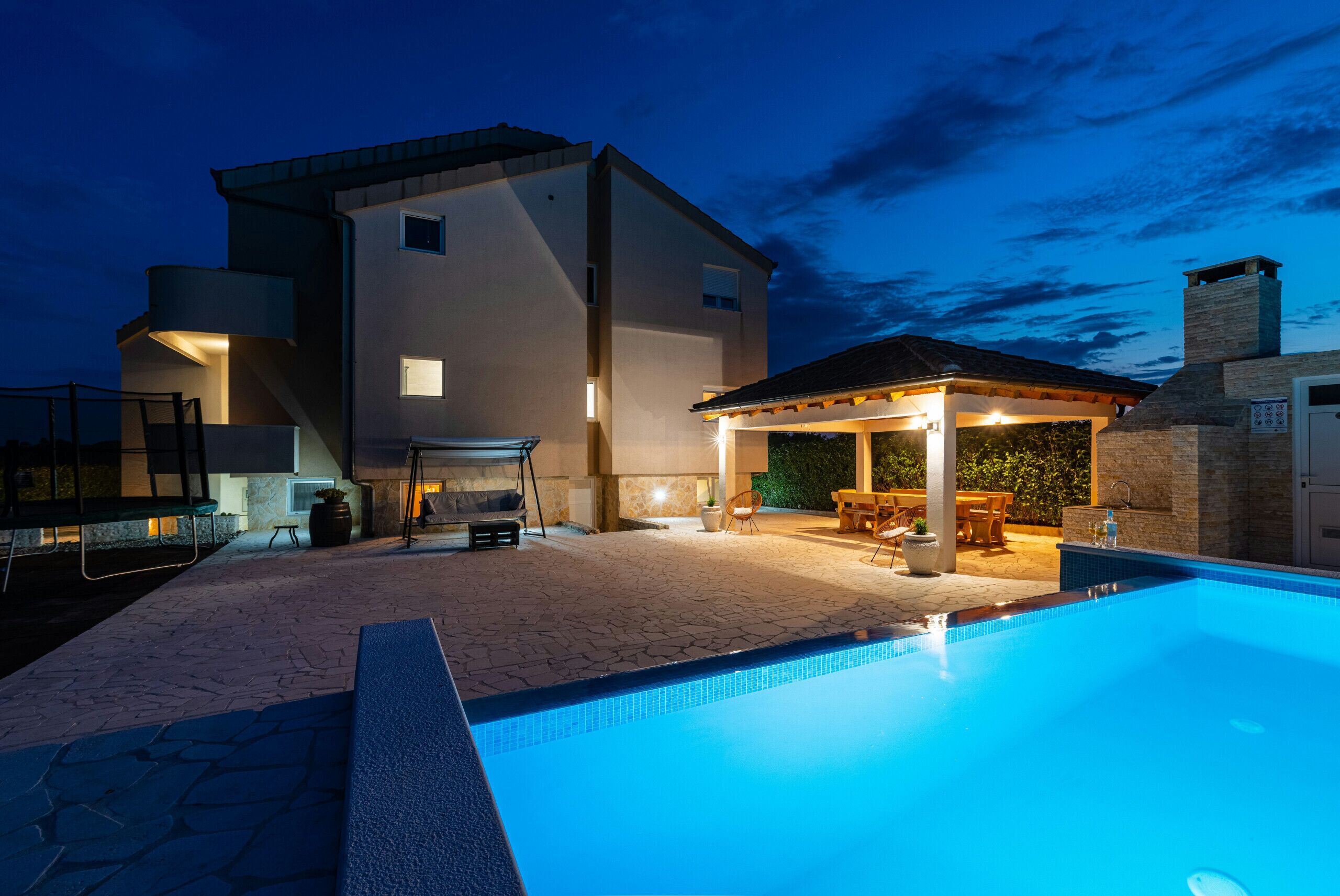 A modern house with a swimming pool, outdoor seating, and a barbecue area.