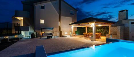 A modern house with a swimming pool, outdoor seating, and a barbecue area.