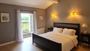 Ein Schlafzimmer mit einem Bett, zwei Nachttischen, einem Fenster mit Vorhängen und Wandlampen.