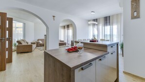 A modern kitchen with a central island, a dining area with a table and chairs, and a living room with a sofa and a coffee table. - Villa Olive Garden (Benkovac)