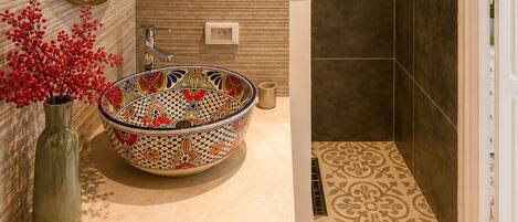 A bathroom with a large, ornate sink, a mirror, and a shower area.